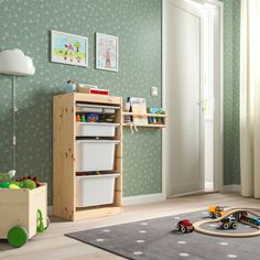 a child's playroom with toys and storage containers on the floor in front of green wallpaper