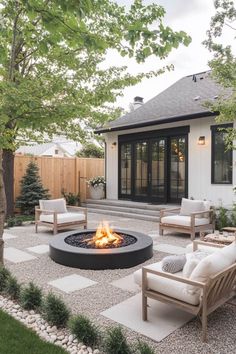 an outdoor fire pit in the middle of a yard with chairs and tables around it