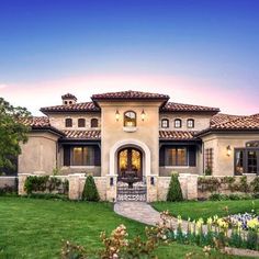 this is an image of a beautiful house in the evening time with flowers on the front lawn