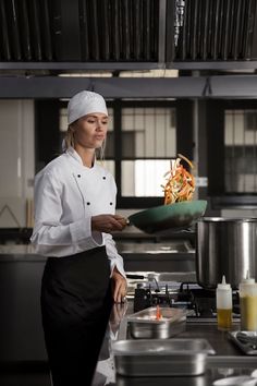 a woman in a chef's uniform holding a pan with food on it