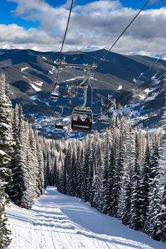 a ski lift with two people on it going down a snowy hill in the mountains