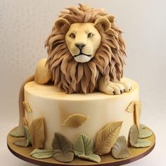 a cake decorated with a lion head and leaves on it's side, sitting on top of a table