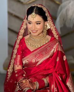 a woman wearing a red and gold bridal outfit