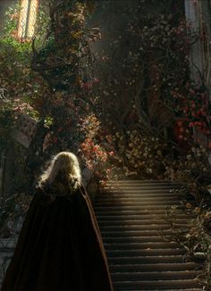 a woman in a red cape is walking down some stairs with flowers on the wall