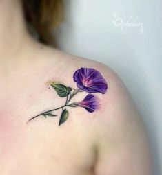 a woman's shoulder with a purple flower tattoo on the left side of her chest