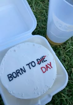 a cake with the words born to die on it in a plastic container next to two drinks