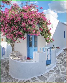 a white house with blue doors and pink flowers