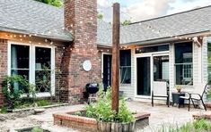 a brick house with an outdoor patio and seating area next to the front door is lit by string lights