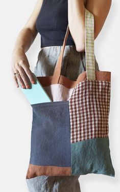 a woman holding a tote bag made out of patchwork fabric