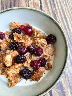 a bowl filled with granola and fruit on top of a wooden table