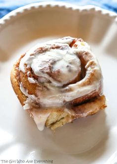 a cinnamon roll with icing on a white plate