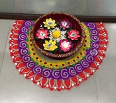 a colorful plate with flowers on it sitting on a counter top next to a vase