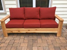 a wooden couch sitting on top of a brick patio