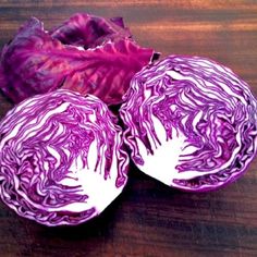 three red cabbages sitting on top of a wooden table