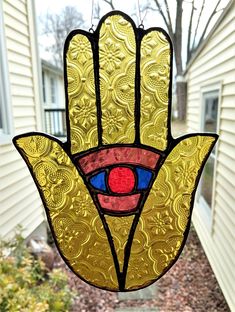 a stained glass hamsa hanging in front of a house