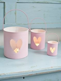 three pink buckets with hearts on them are sitting on a table next to each other