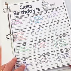 a hand holding a binder that has a class birthday's list on it