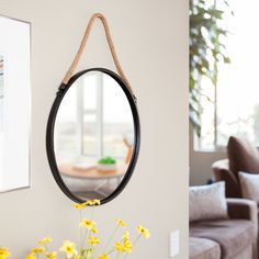 a mirror hanging on the wall next to a vase with yellow flowers in front of it