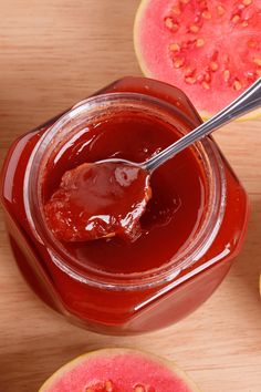 a spoon in a jar filled with ketchup next to sliced watermelon