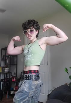 a young woman flexing her muscles while standing in a room with a green balloon