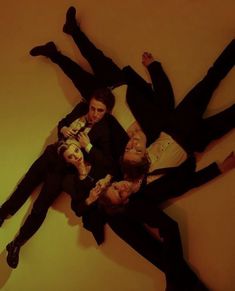 four people laying on the floor with their arms around each other and one person holding a cell phone