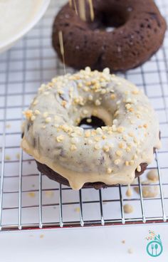 two doughnuts on a cooling rack with sprinkles and one donut