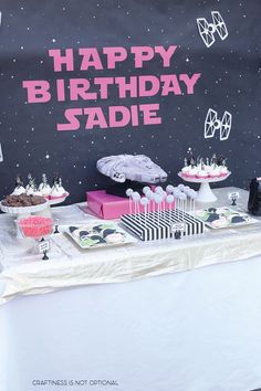 a birthday table with cake and cupcakes on it