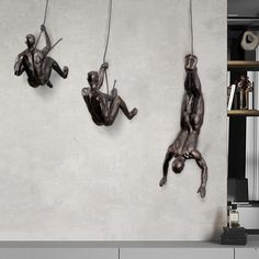 two statues hanging from strings on a wall