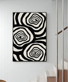 a black and white painting hanging on the wall in a living room next to stairs