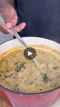 a person holding a spoon in a bowl of soup