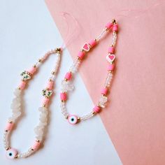 two pink and white beaded necklaces sitting next to each other on a table