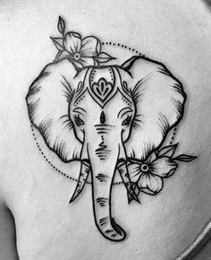 an elephant tattoo on the back of a woman's shoulder, with flowers around it