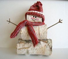 a snowman made out of birch logs wearing a red hat and scarf