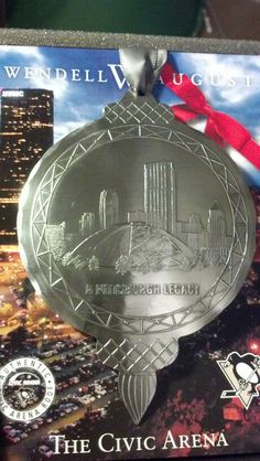 a silver medal with a red ribbon around it's neck and an image of a city in the background