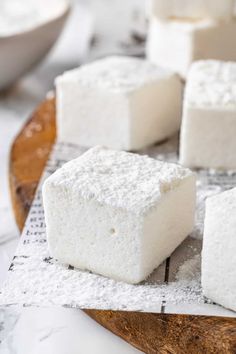 several pieces of white cake sitting on top of a wooden cutting board with powdered sugar