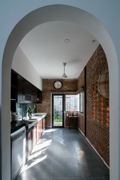 an archway leading to a kitchen and dining area with a clock mounted on the wall