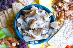 a blue bowl filled with food next to crackers and grapes