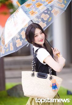 a young woman holding an umbrella with teddy bears on it's side and smiling at the camera