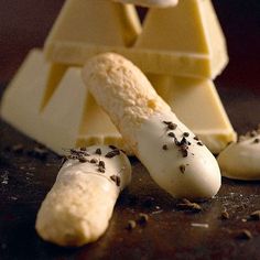 some pieces of food that are on top of a wooden table with cheese and other items