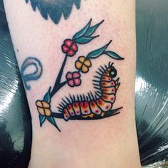 a very cute small caterpillar tattoo on the leg with flowers and music notes