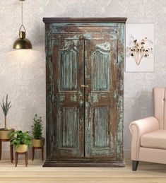 an old wooden armoire sitting next to a chair and potted plant in a living room