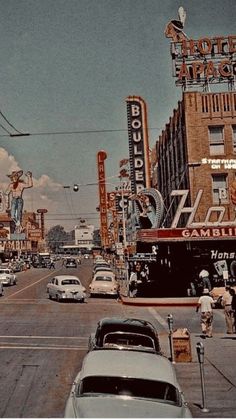 an old photo of cars driving down the street in front of some buildings and neon signs