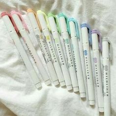 six pens are lined up in a row on a white sheet, with the words write it all over them