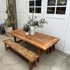 a wooden table with two benches and a potted plant on the outside wall next to it