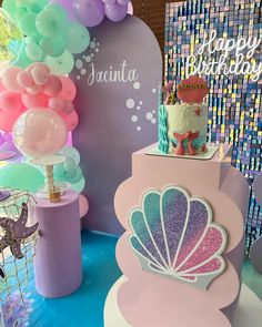 there is a birthday cake on top of a stand with balloons and confetti