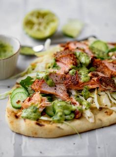 a pizza topped with meat and veggies next to a bowl of sauces