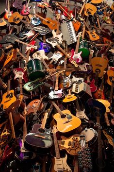 a large pile of guitars and electric guitars