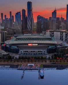 an aerial view of a stadium with the sun setting in the background and skyscrapers