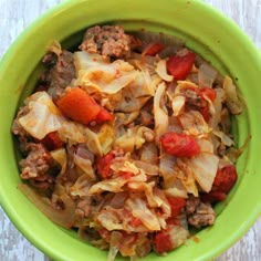 a green bowl filled with cabbage and meat