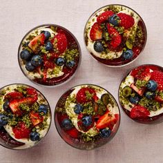 four desserts are arranged in small bowls on a white tablecloth, top view